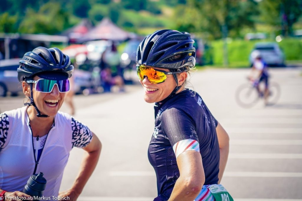 Zwei Damen lachend auf einem Platz nach dem Rennradfahren